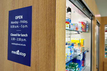 Closeup of shelf with products at MedStop, MIT Health’s OTC kiosk. A sign on the side of the shelf shows MedStop hours