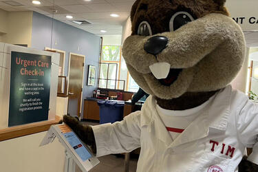 MIT Mascot Tim the Beaver standing in MIT Health’s Urgent Care registration area