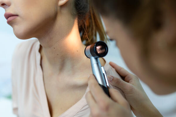 Dermatologist checks mole on patient