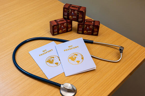 a stethoscope and two pamphlets titled "My passport" on a table next to three small boxes decorated like suitcases