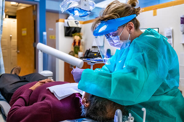 Side view of a dental clinician treating a patient who is reclining in a dental treatment chair